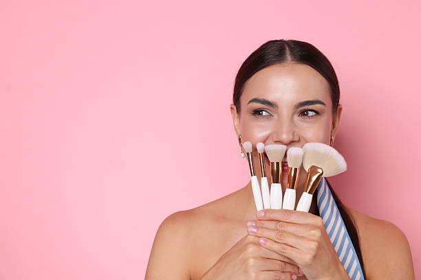 istock Beautiful woman with makeup brushes on pink background, space for text 2237751233