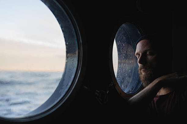 istock Man looking out ship porthole at sea 2237756513