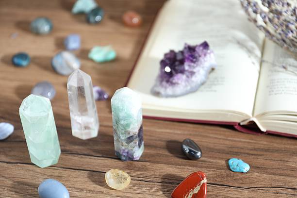 istock Different healing stones and book on wooden table, closeup 2237757178
