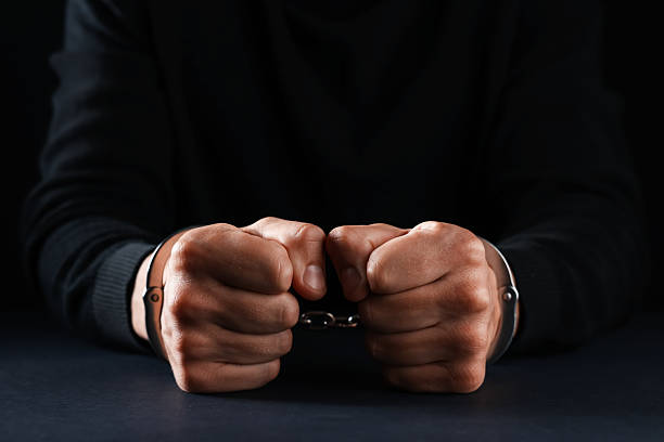 istock Man in metal handcuffs at table on black background, closeup 2237757344
