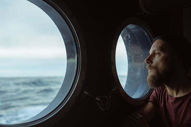 istock Man looking out ship porthole at sea 2237757355