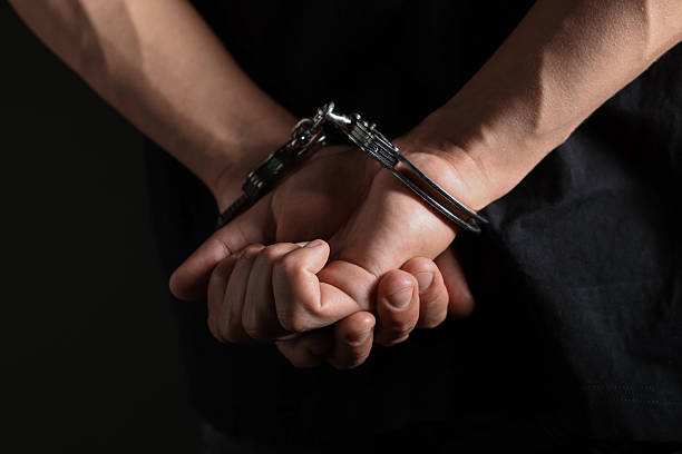 istock Man in metal handcuffs on black background, closeup 2237757500
