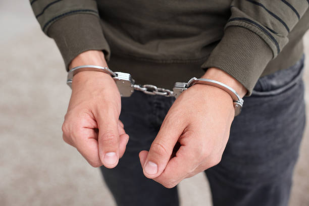 istock Man in metal handcuffs on blurred background, closeup 2237757515