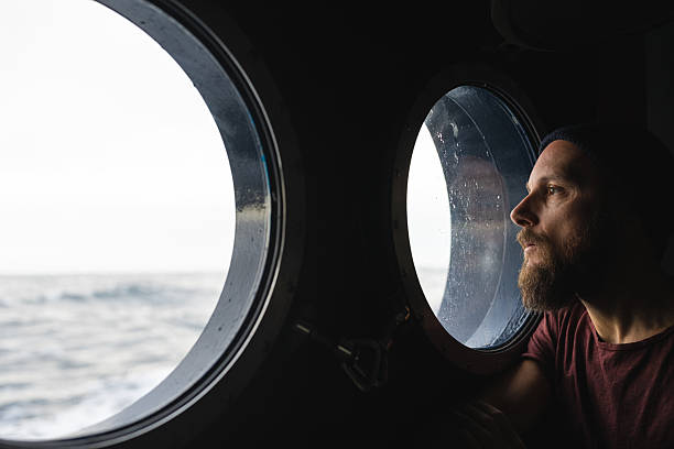 istock Man looking out ship porthole at sea 2237761389