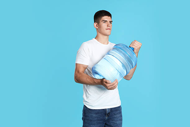 istock Delivery man with cooler bottle of water on light blue background 2237762795