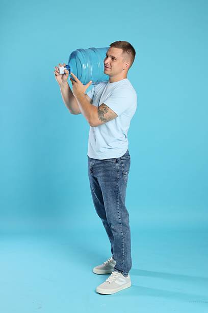 istock Delivery man with cooler bottle of water on light blue background 2237762937