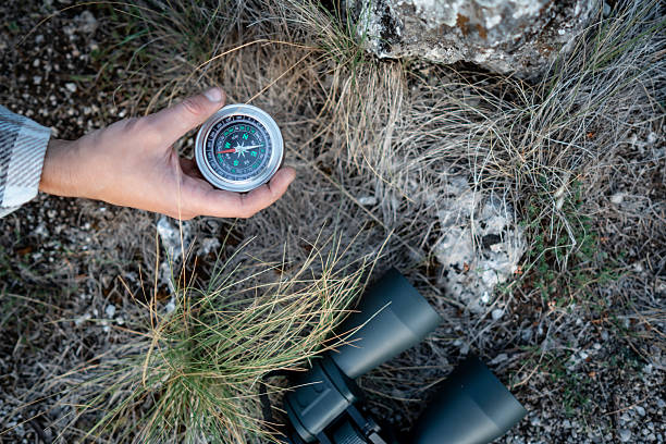 istock Person Holding a Compass Over Rugged Terrain With Binoculars and Backpack Gear Outdoors Adventure 2237764089
