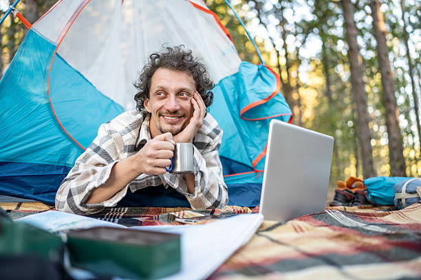 istock Relaxed Camper Working Outside, Drinking Coffee by Laptop Inside a Blue Tent in the Forest 2237765800