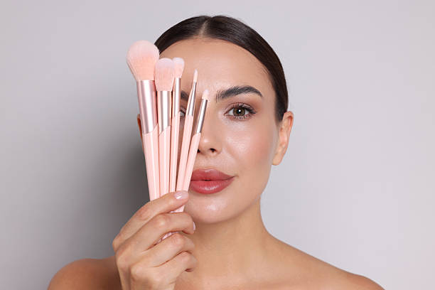 istock Beautiful woman with makeup brushes on light grey background 2237765966