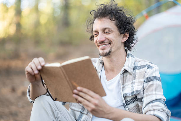 istock Relaxed Man Reading a Journal While Camping in a Forest Campsite 2237766022