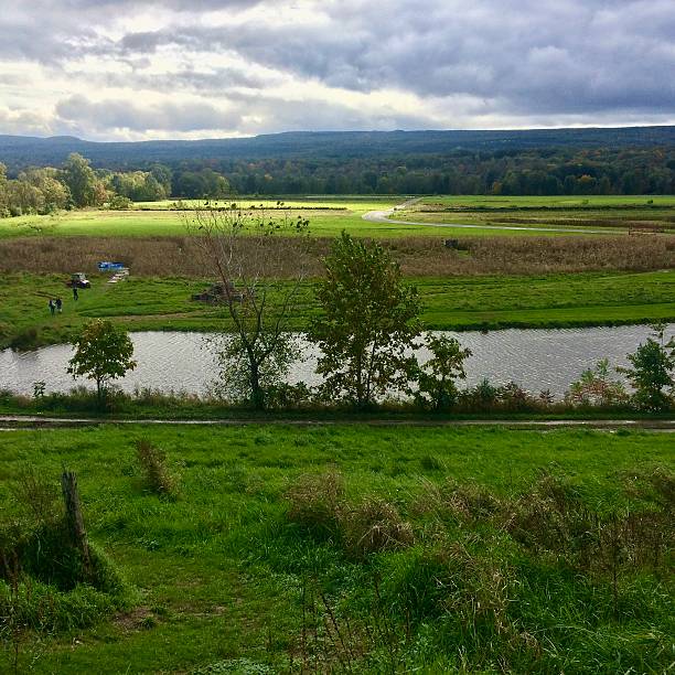 istock Dramatic Clouds Over Farmland and Stream – Green Fields, Trees, Water, and Mountains in Rural Autumn Landscape 2237777673