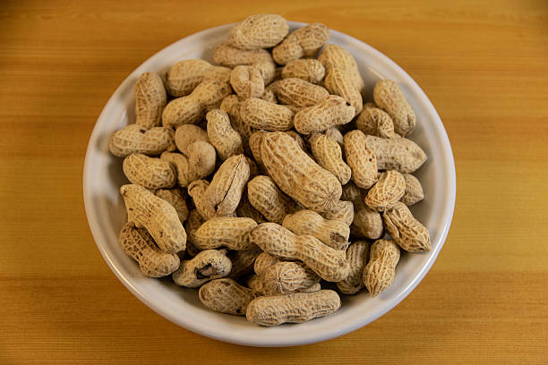 istock Photograph, one plate of salt peanuts is on a light brown table 2237783567
