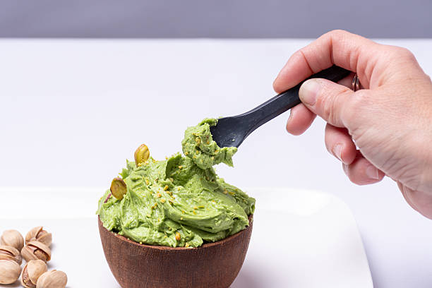 Hand scooping a spoonful of pistachio ice cream from a bowl.