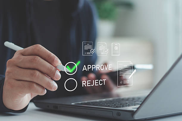 istock Businessman hand using digital pen with laptop and smartphone selecting approve option on virtual screen. Concept of online document approval, electronic signature, workflow, digital business process. 2237788880