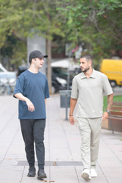 istock Two men walking down a sidewalk, one wearing a blue shirt 2237796579