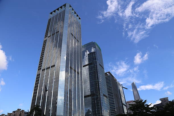 A tall building with a lot of windows. The sky is blue and there are some clouds. The building is in the middle of a city