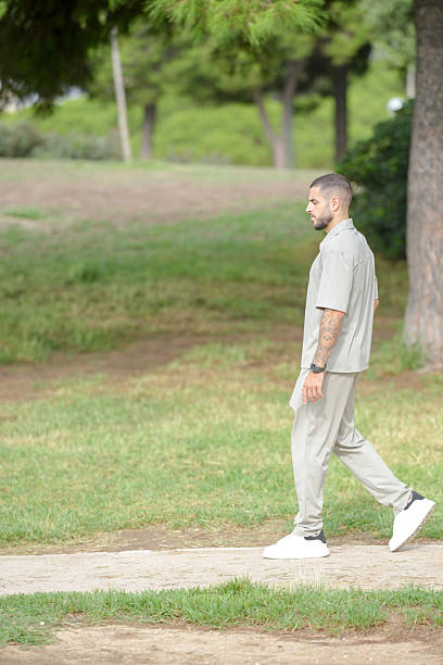 istock A man in a tan shirt and khaki pants walks through a park 2237803095