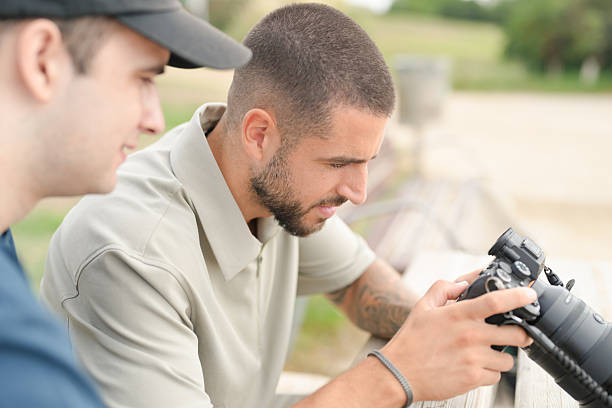 istock Two men are sitting on a bench, one of them holding a camera 2237803621