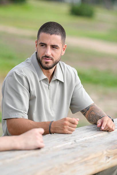 istock A man with a beard and a shirt on sits at a picnic table 2237808478
