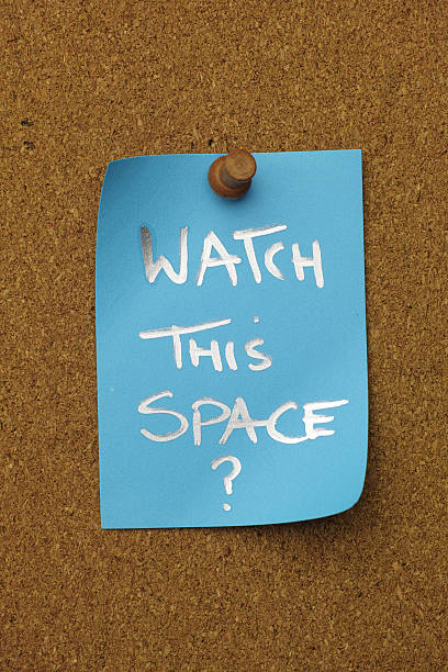istock Blue paper note pinned to a cork message board, with the short phrase 'WATCH THIS SPACE ?' written on it. 2237810880