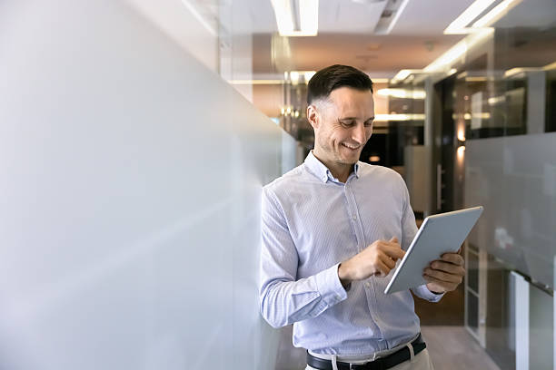 istock Businessman standing in modern office hallway with tablet device 2237815393