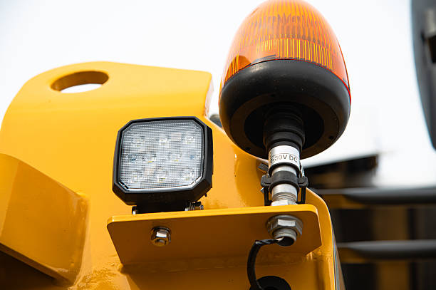 Close up view of a bright amber warning beacon and a modern led work light