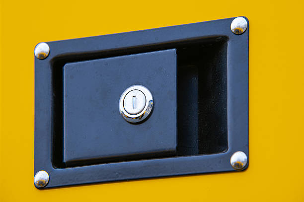 Close-up of a security lock and handle on a bright yellow industrial machine panel