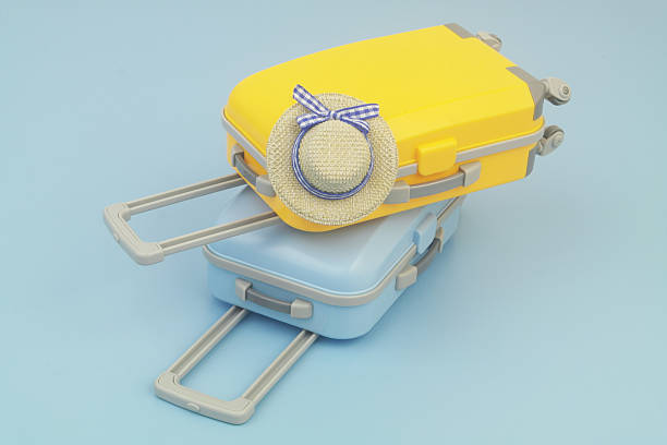 Orange and blue travel suitcase with beach hat on blue background. Copy space for text. Vacation and travel concept.