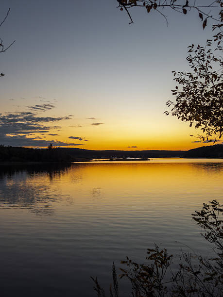 istock A Serene Sunset Over a Calm Lake, Framed by Silhouetted Trees and Golden Reflections 2237818100