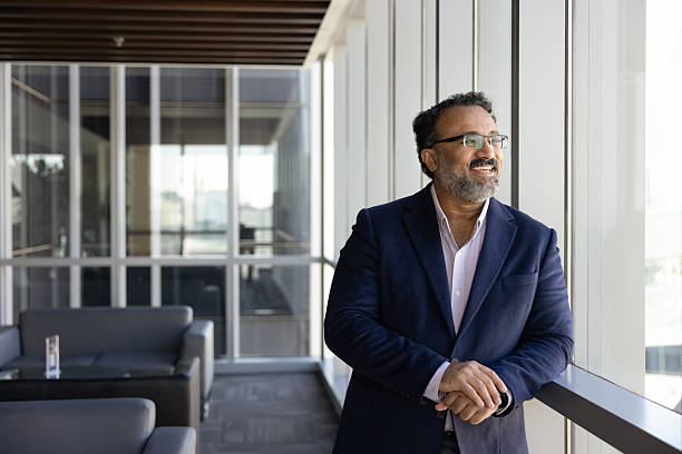 istock Middle-aged businessman stands by office window looking outside with smile 2237819032