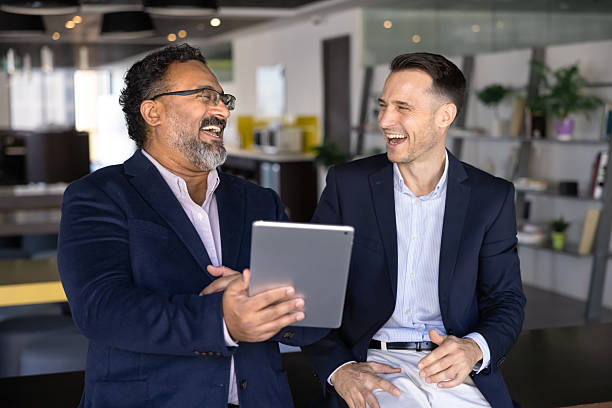 istock Two businessmen laughing together while holding tablet 2237822110