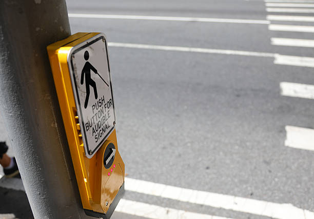 istock yellow pedestrian button on a metal pole on a sidewalk next to a traffic light 2237823058