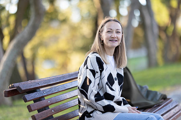 istock Woman smiling sitting on park bench wearing braces 2237826050