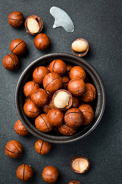 istock Macadamia nuts in shell. Black ceramic bowl with nuts. Top view. Close-up, on slate background. 2237829648