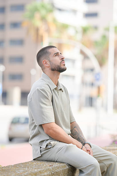 istock A man in a tan shirt and pants is sitting on a wall 2237831711