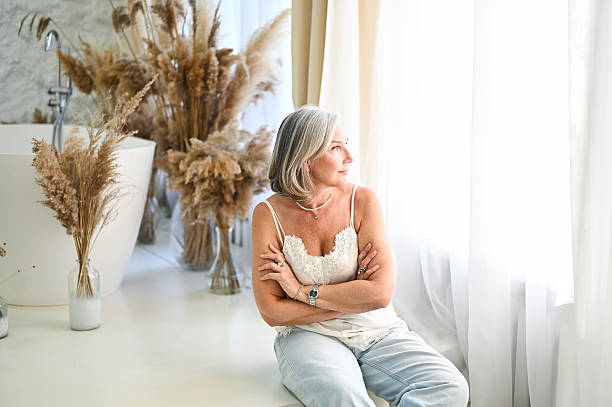 Mature adult woman with grey hair pensive in a stylish bathroom