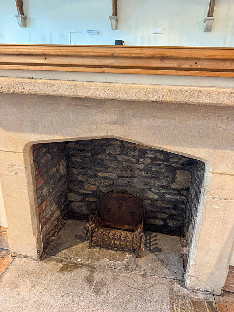 Stock photo shows an antique stone fireplace with ornate mantle and mantlepiece, highlighting traditional hearth design used for fire heating in classic interiors. This vintage feature adds timeless elegance and rustic charm to interior design