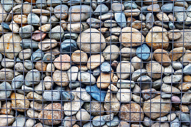 istock Assorted river stones behind wire mesh fence for garden landscap 2237839829