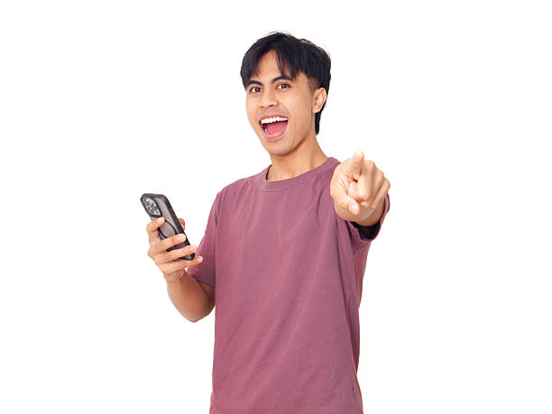 istock Young Asian man holding smartphone and pointing at the camera on isolated white background, concept of mobile app promotion, digital lifestyle, and communication. 2237839948