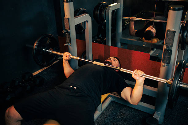 istock Man Lifts Barbell on Bench Press in Gym During Workout Session 2237840675