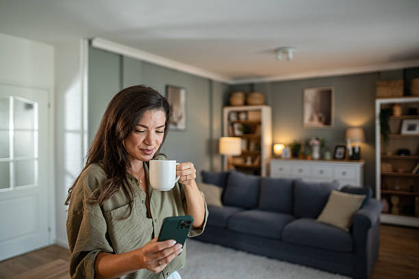 istock Woman drinking coffee and using smartphone at home 2237841024