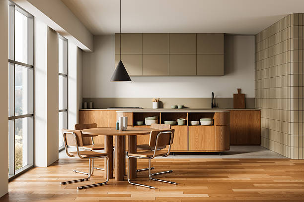 Minimalist wooden kitchen interior design with round dining table, modern cabinetry, and large windows in warm daylight ambiance. 3D Rendering