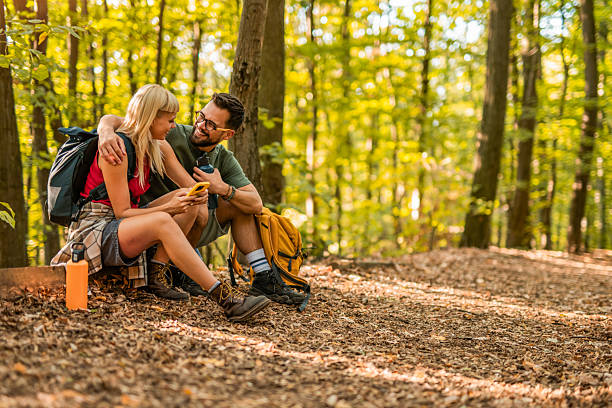 istock Happy couple using mobile phone while hiking together in a forest. 2237847344