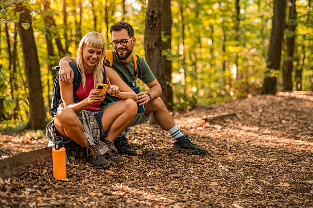 istock Happy couple using mobile phone while hiking together in a forest. 2237848325