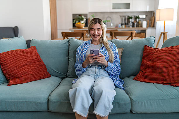istock Woman relaxing on sofa laughing at phone screen 2237857790