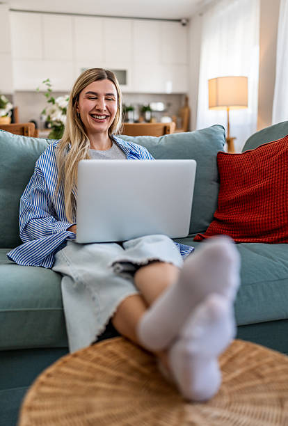 istock Woman smiling while using laptop on sofa at home 2237858359