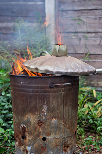 istock Fire burning in a rusty metal bin with a lid amid a garden setting. 2237864751