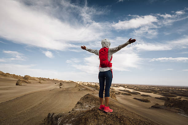 Successful woman trail runner open arms on sand desert dunes