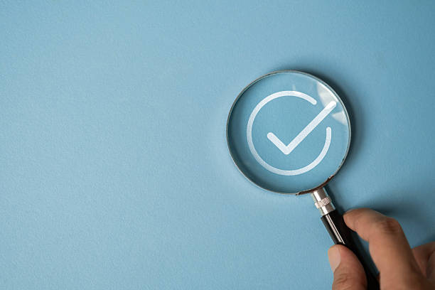 istock Hand holding magnifying glass highlighting a check mark icon on blue background. Concept of verification, approval, validation, quality control, success, or completed tasks. 2237869337
