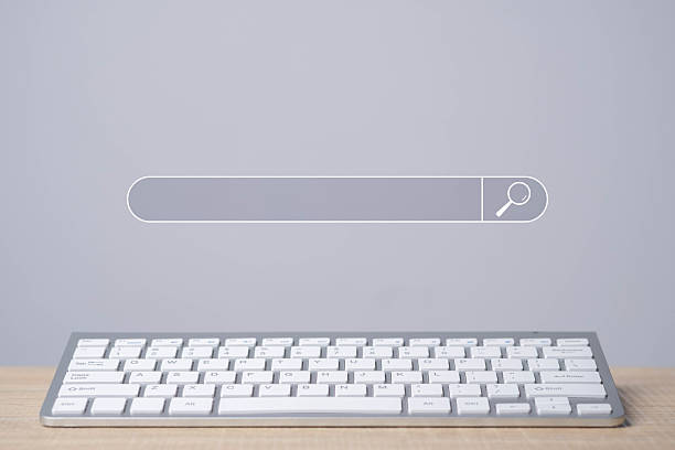 istock Search bar interface above a white computer keyboard on wooden table. Concept of internet browsing, online research, search engine optimization (SEO), digital marketing, and information access. 2237869439